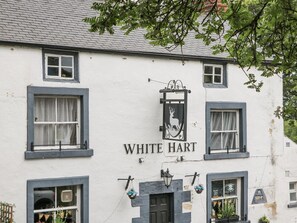 Ein Gebäude mit der Aufschrift 'WHITE HART' und einem schwarzen Schild mit einem Hirschlogo.