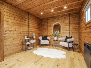 A cozy log cabin room with a white sofa set, a white shag rug, and a mirror on the wall. - Badger's Burrow, Edith Weston (Oakham)