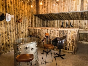 A rustic interior with wooden walls, a bar area, and leather chairs.
