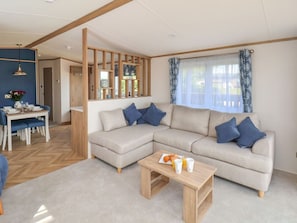 A modern living room with a sectional sofa, a dining table, and a coffee table. - Fir Lodge in Whitby, Yorkshire (Whitby)