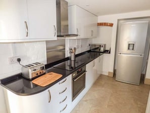 Eine moderne Küche mit weißen Schränken, einer schwarzen Arbeitsplatte, einem Toaster, einer Mikrowelle und einem Edelstahlkühlschrank.