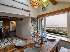 A dining area with a view of the sea, a stone wall, and a rustic wooden table. - Pengarreg in Barmouth, Gwynedd (Barmouth)