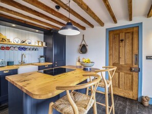 A kitchen with wooden beams, a central island, and a blue wall. - Pengarreg in Barmouth, Gwynedd (Barmouth)