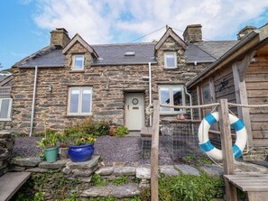 A stone house with a wooden exterior, a front door, and a small porch area. - Pengarreg in Barmouth, Gwynedd (Barmouth)
