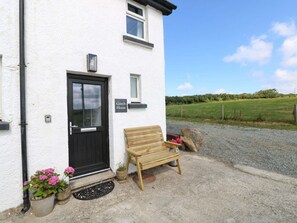 A white building with a black door, a bench outside, and a sign that reads 'Coach House.' - Coach House Cottage, Broad Haven (Haverfordwest)