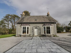 A stone house with a central door, two chimneys, and a gravel driveway. - Auchenvhin in Dalbeattie, 5bed (Dalbeattie)