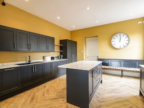 A modern kitchen with dark cabinets, a marble countertop island, and a large wall clock. - Auchenvhin in Dalbeattie, 5bed (Dalbeattie)