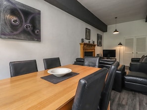 Un comedor con una mesa de madera, sillas negras y un cuenco blanco.