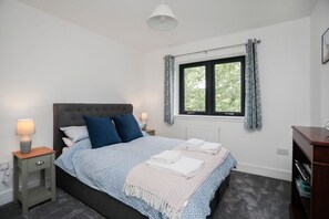 A bedroom with a bed, bedside lamps, a window with curtains, and a radiator. - 26 Strathtay Lodges, Aberfeldy (Aberfeldy)