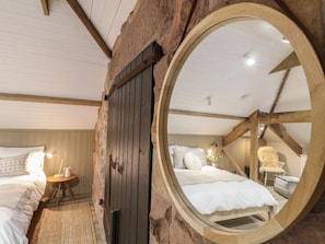 Ein Schlafzimmer mit einem runden Spiegel, einem Bett, einem Nachttisch und einem Sessel.