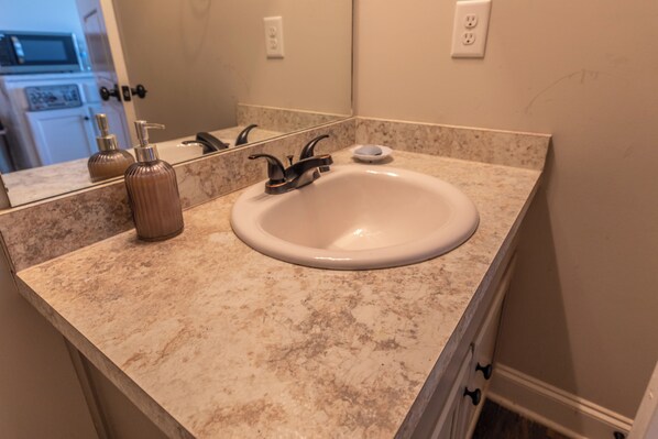A bathroom with a sink, mirror, and countertop.