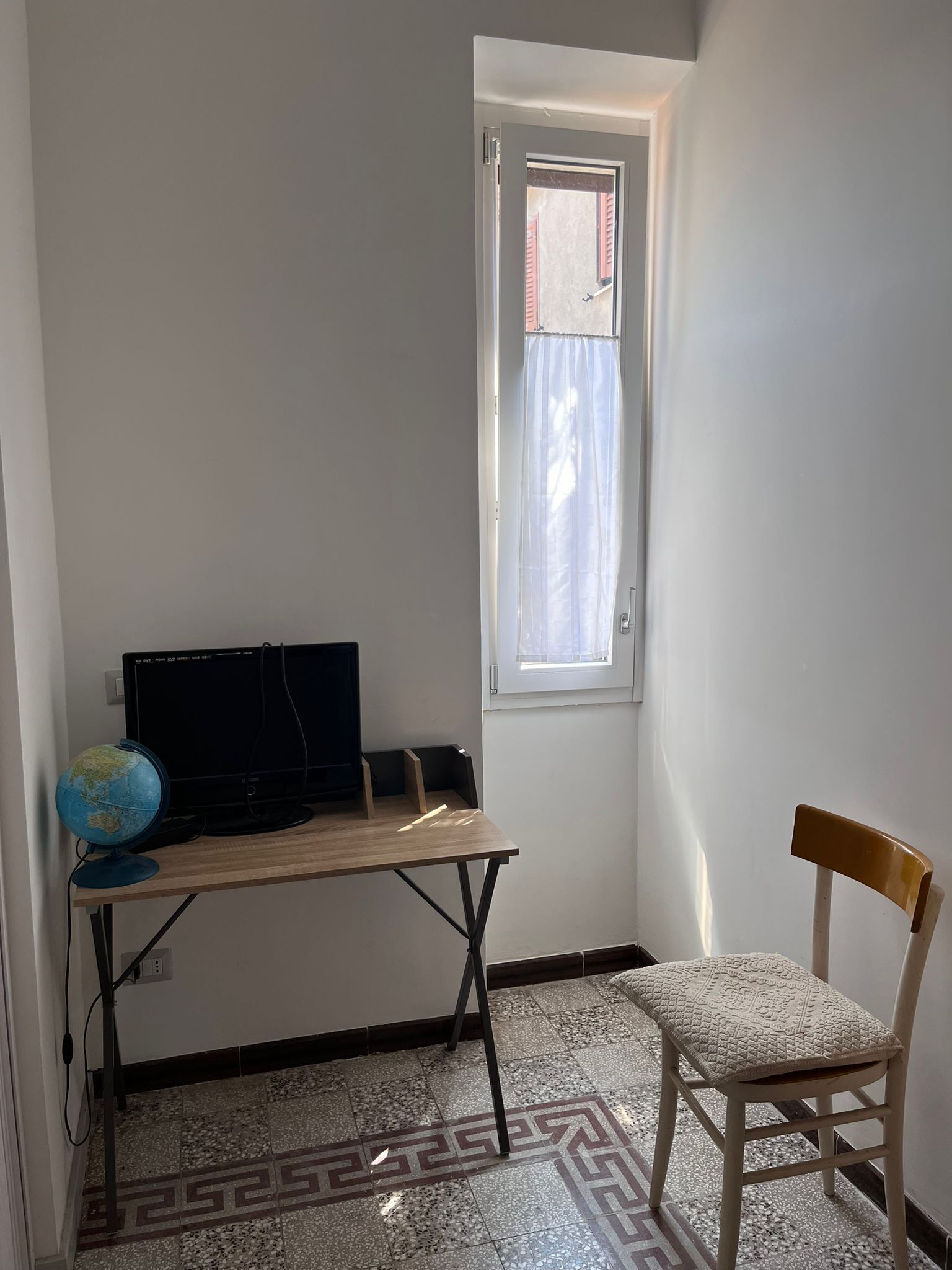 A room with a desk, a chair, a globe, and a television.