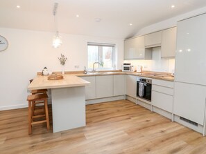 Eine moderne Küche mit einer Holztischinsel, weißen Schränken und einem eingebauten Backofen.