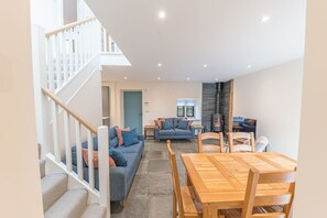 Un vaste espace de vie comprenant un escalier, une table à manger en bois et deux canapés.