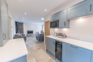 A modern kitchen with grey cabinets, a microwave, a toaster, and a refrigerator.