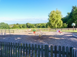 A playground with swings, a climbing structure, and a seesaw. - Amelia Cottage, Battle (Battle)