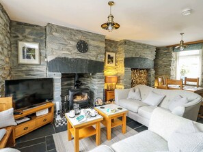 A living room with a stone wall, fireplace, sofa, TV, and wooden furniture.