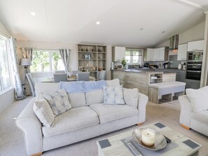 A modern living room with a sofa, coffee table, and kitchen area with cabinets and appliances.