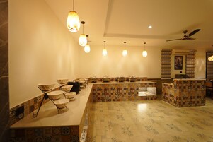A restaurant with a long counter, hanging pendant lights, and patterned tile flooring.