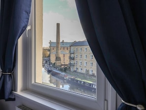 A window view of a canal with buildings and a tall chimney. - 43 Brook Street, Skipton 2 bed (Skipton)