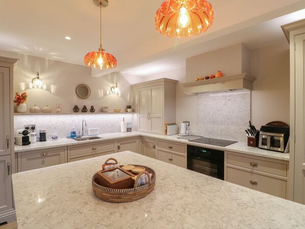 A modern kitchen with a marble countertop, built-in appliances, and pendant lighting. - The Coach House, Holloway (Matlock)