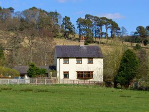 A two-story house with a sloped roof, a chimney, and a fenced yard. - Hartam House, Falstone (Hexham)