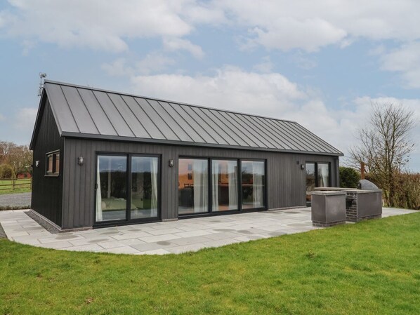 A modern building with a sloped roof, large glass windows, and a patio area.