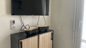 Ein an der Wand befestigter Fernseher, eine Kommode mit zwei verzierten Schalen und eine Steckdose.