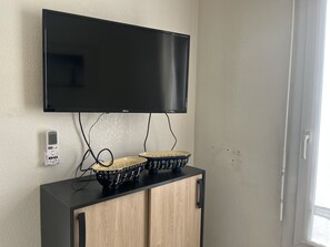 Ein an der Wand befestigter Fernseher, eine Kommode mit zwei verzierten Schalen und eine Steckdose.