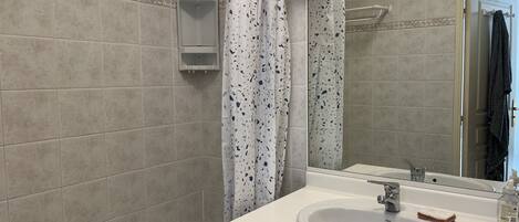 A bathroom with a bathtub, a sink, a mirror, and a shower curtain.