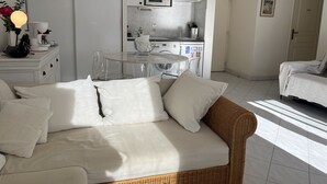 Ein moderner, gut beleuchteter Raum mit einer Couch, einem Esstisch und einer Küchenzeile.