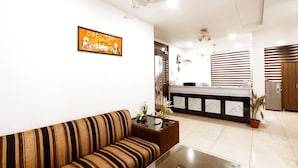 Un salon moderne avec un canapé, une table basse, un ventilateur de plafond et un coin cuisine à l’arrière-plan.