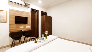 Une chambre d’hôtel comprenant un lit, un bureau avec deux chaises, une télévision et un appareil de climatisation.