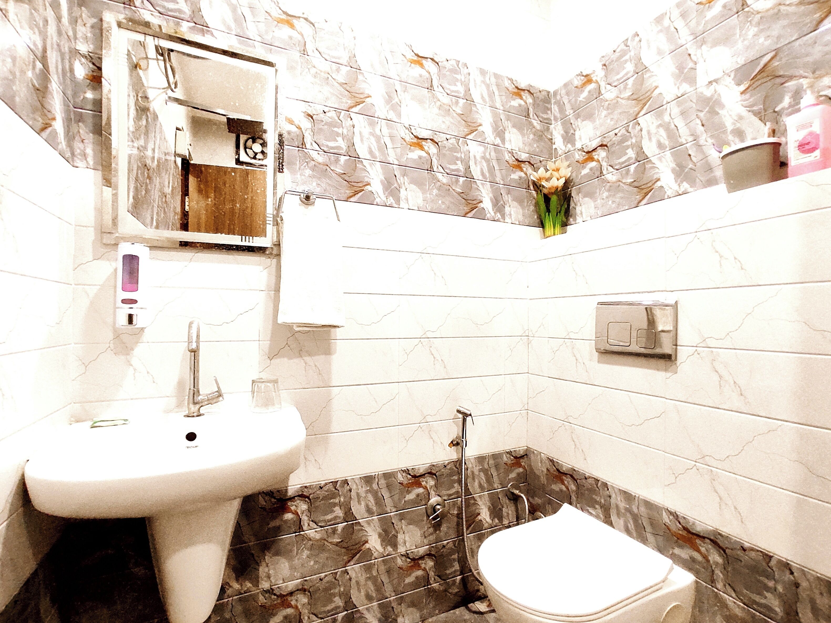 A bathroom with a sink, mirror, toilet, and shower.