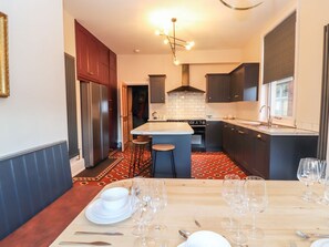A modern kitchen with a central island, dark cabinetry, and a patterned floor. - Livingstone House, Llandudno (Llandudno)