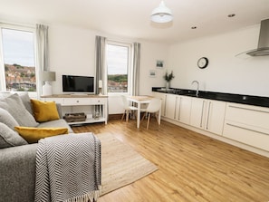 A modern living room with a sofa, TV, and dining area. - Stunning Marina View in Whitby (Whitby)
