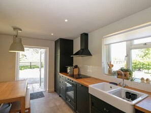 Una cocina moderna con encimera de madera, armarios negros, horno empotrado y un ventanal que proporciona luz natural.
