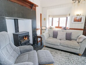 Ein gemütliches Wohnzimmer mit Kamin, einer Couch und einem Sessel.