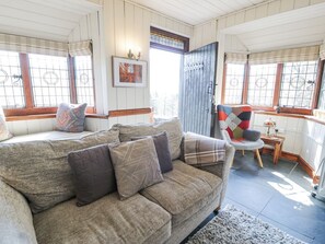 Ein gemütliches Wohnzimmer mit Sofa, Sessel, Teppich und einer Tür.
