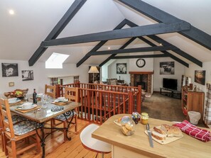 A dining area with a wooden table, chairs, and a red railing. There is a fireplace in the background and a clock on the wall. - The Haven is in Northumberland (Berwick-upon-Tweed)
