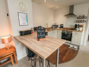 A modern kitchen with a wooden table, a welcome sign, a clock, and a map on the wall. - The Annexe, Bridlington, North Yorkshire. (Bridlington)