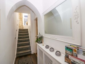 A staircase leading to a room with a white console table holding books and decorative items. - Acorn Cottage is in Windermere (Windermere)