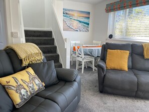Ein Wohnzimmer mit einer Couch, einem Esstisch und einer Treppe.