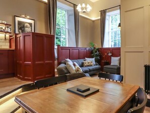 A dining area with a wooden table, chairs, a sofa, and a red cabinet. - The Court, Ingleton, Yorkshire (Carnforth)