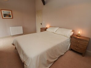 Ein Schlafzimmer mit Bett, Nachttischen, Heizkörper, Tür und einem gerahmten Bild an der Wand.