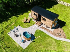 Une cabane en bois dotée d’un bain à remous, d’un espace extérieur aménagé et d’un chemin de gravier.