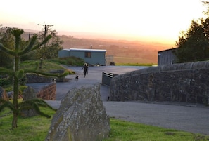 A stone wall, a small building, and a person walking a dog.