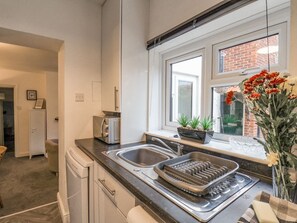 Eine moderne Küche mit einer Spüle, einem Toaster, einem Geschirrgestell und einem Fenster mit Blick auf ein Backsteingebäude.
