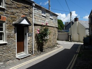 A stone cottage with a small porch, a sign reading 'SOURISE COTTAGE,' and a rose bush in front. - Sunrise Cottage, Padstow (Padstow)