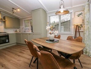 A kitchen with a wooden table, chairs, and a pendant light. - Robin's Lodge, Windermere (Windermere)